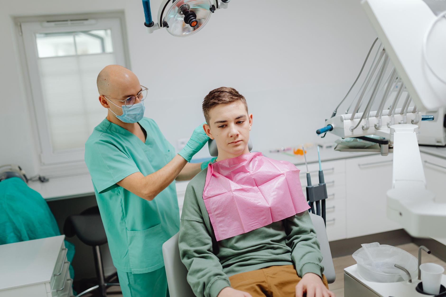 Teenager in a dental chair receiving orthodontic care from a masked dentist