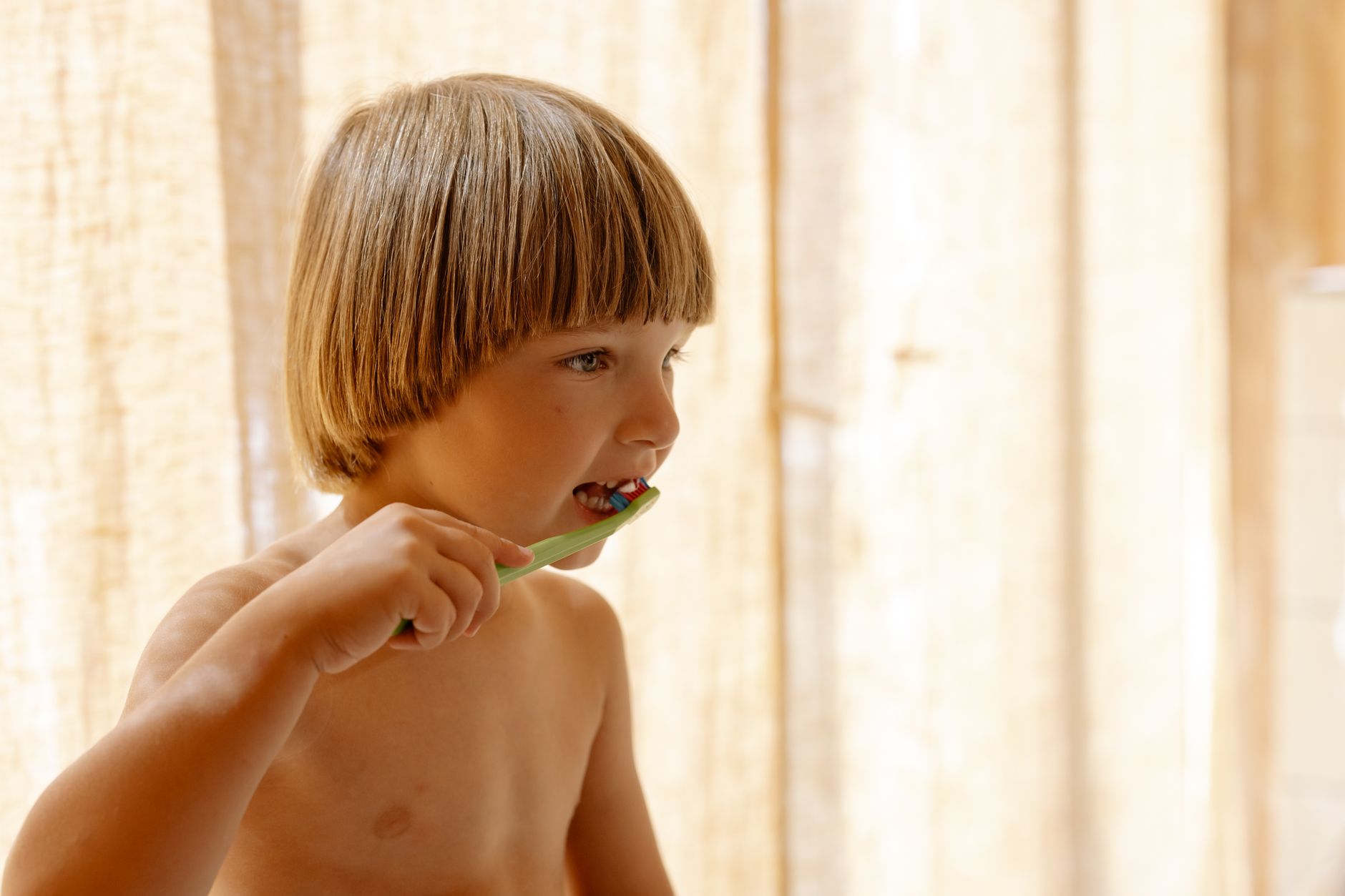 Young boy brushing his teeth indoors in soft natural light
